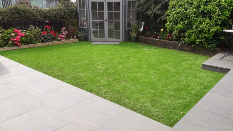 Aged anthracite porcelain patio with artificial grass and a summerhouse
